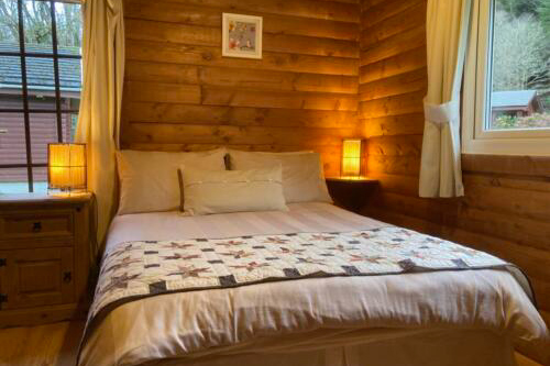 cozy wooden bedroom with a bed and quilted blanket warm lighting and large window for a relaxing retreat 4 comfort 4 relaxation 4 rustic 4 cabin